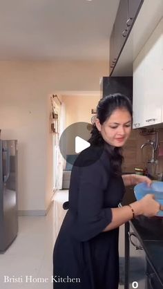 a woman is washing dishes in the kitchen