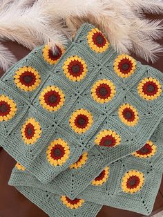 three crocheted sunflower afghans on top of a table with white fur