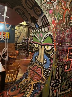 an artistic mural on the side of a wall in a restaurant with wooden tables and chairs