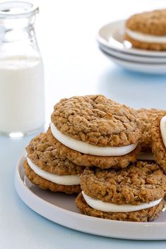 cookies with marshmallows are stacked on a plate next to a glass of milk