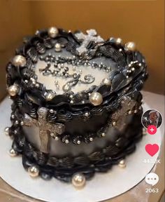 a black and white decorated cake on top of a table with silver pearls around the edges