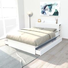 a white bed sitting on top of a hard wood floor next to a wall mounted painting