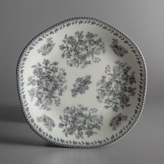 a black and white plate with floral designs on the rim, sitting on a gray surface