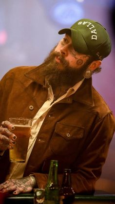 a man sitting at a bar with a beer in his hand and tattoos on his arm