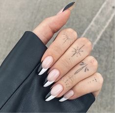 a woman's hand with white and black manies on her nails, holding a black purse