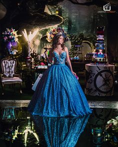 a woman in a blue dress standing next to a cake