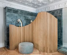 a room that has a wooden wall in the corner and a round ottoman on the floor