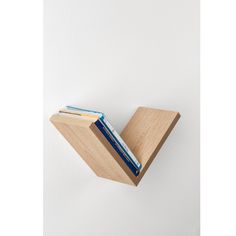 two books are placed on the edge of a wooden book holder, which is attached to a white wall