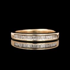 two gold wedding bands with baguets on each side, set against a black background