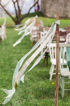 a row of chairs sitting on top of a lush green field next to a wooden pole