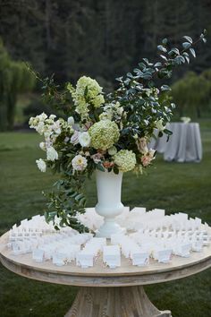 a white vase filled with lots of flowers on top of a table covered in cards