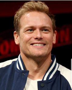 a close up of a person wearing a blue and white jacket with a smile on his face