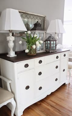 a white dresser with two lamps on top of it