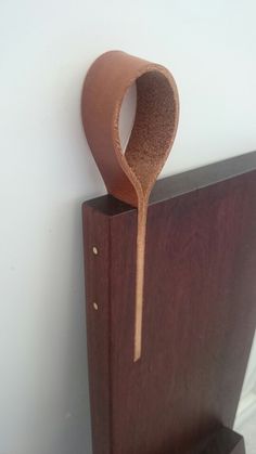 a wooden object with a spoon sticking out of it's back end on a white wall