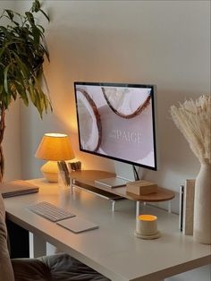 A cozy home office featuring a minimalist desk setup with neutral colors, warm lighting from a small lamp, a wooden monitor stand, and green plant decor, creating an elegant and serene workspace. Productive Work, Cozy Desk, Cozy Office, Cozy Home Office, Deco Studio, Aesthetic Space, Warm Lighting, Office Room Decor, Home Office Ideas