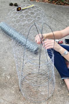 a woman sitting on the ground next to a wire fence with a baseball bat in it