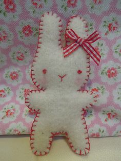 a white stuffed animal sitting on top of a pink and white flowered bed sheet