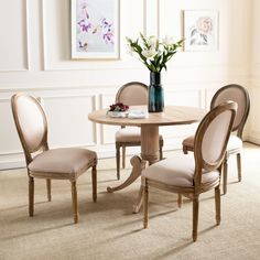 a dining room table with four chairs and a vase on top of the table in front of it