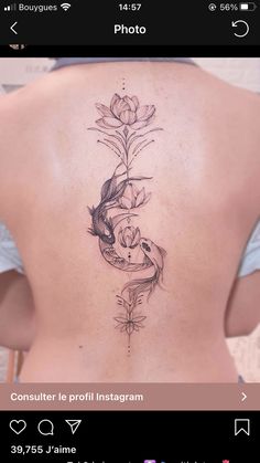 the back of a woman's body with flowers and fish tattoo on her lower back