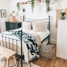 a bedroom with white walls and black metal bed frame, potted plants on the wall