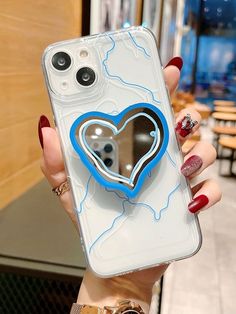 a woman holding up a phone case with a heart on it