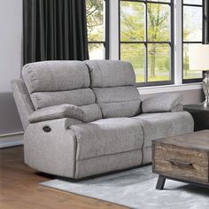 a living room with a gray recliner and coffee table in front of a window