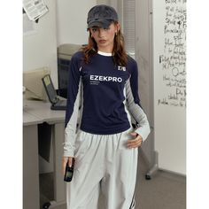 a woman standing in front of a whiteboard wearing a baseball cap and sweatpants