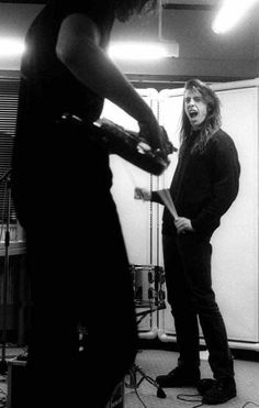 two people standing in a room with guitars