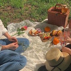 two people sitting on a blanket with food and drinks