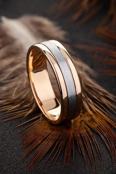 two tone gold and silver wedding rings with feathers on the ground in front of them