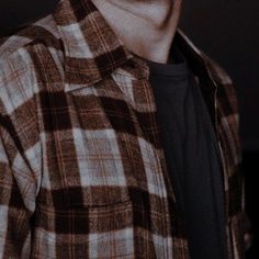 a man wearing a plaid shirt and black t - shirt is looking at the camera