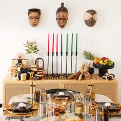 a dining room table with plates and utensils on it, decorated with african masks