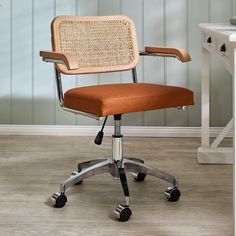 a brown office chair sitting on top of a wooden floor next to a white table