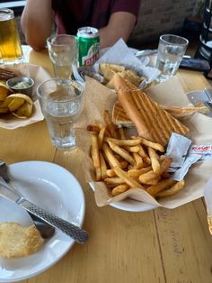 a table topped with lots of food next to glasses and plates filled with food on top of a wooden table