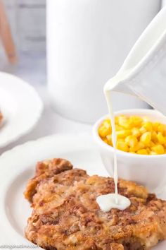 corn and milk being poured onto some food on a plate with another dish in the background