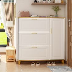 a white dresser sitting in a living room next to a window