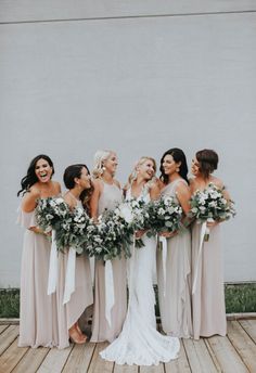 a group of women standing next to each other on a wooden floor holding bouquets