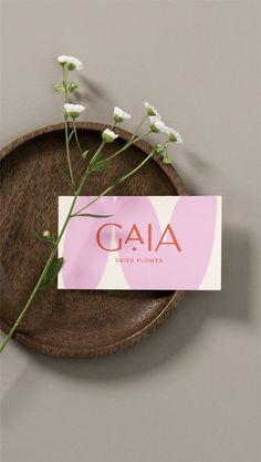 a wooden plate with flowers on it and a card that says gaia direct flower