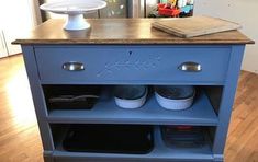 a blue cabinet with two cups on it and a cake plate sitting on top of it