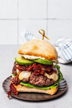 a hamburger with meat, lettuce and cheese on a bun sitting on a plate