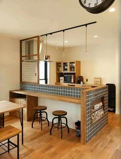 a kitchen with a clock hanging from the ceiling above it and stools at the bar