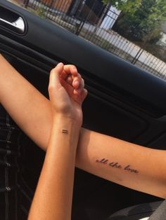 two hands holding each other while sitting in the driver's seat of a car