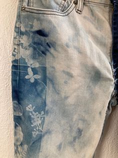 a pair of blue jeans with white flowers on them are hanging up against a wall