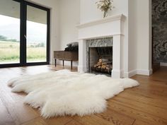 a white sheepskin rug is on the floor in front of a fireplace with glass doors