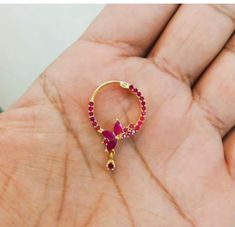 a hand holding a gold ring with red stones