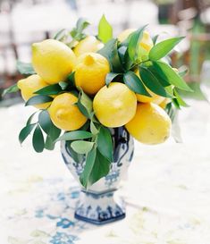 a vase filled with lemons on top of a table