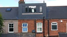 a red brick building with two windows and a clock on the top of it's roof