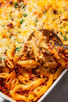 a casserole dish with meat and cheese being scooped from the casserole