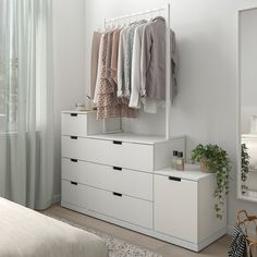 a white dresser with clothes hanging on it