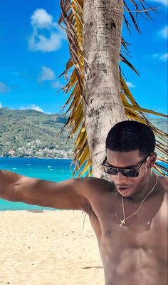 a shirtless man on the beach with his arms out and palm trees in the background